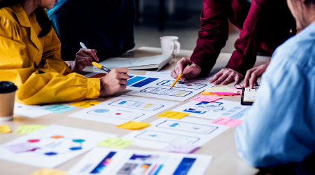 A team is working on physical copies of the UI / UX design layout for a mobile application