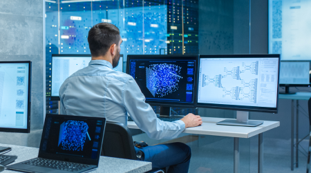 A male IT professional working on multiple screens in an office setting