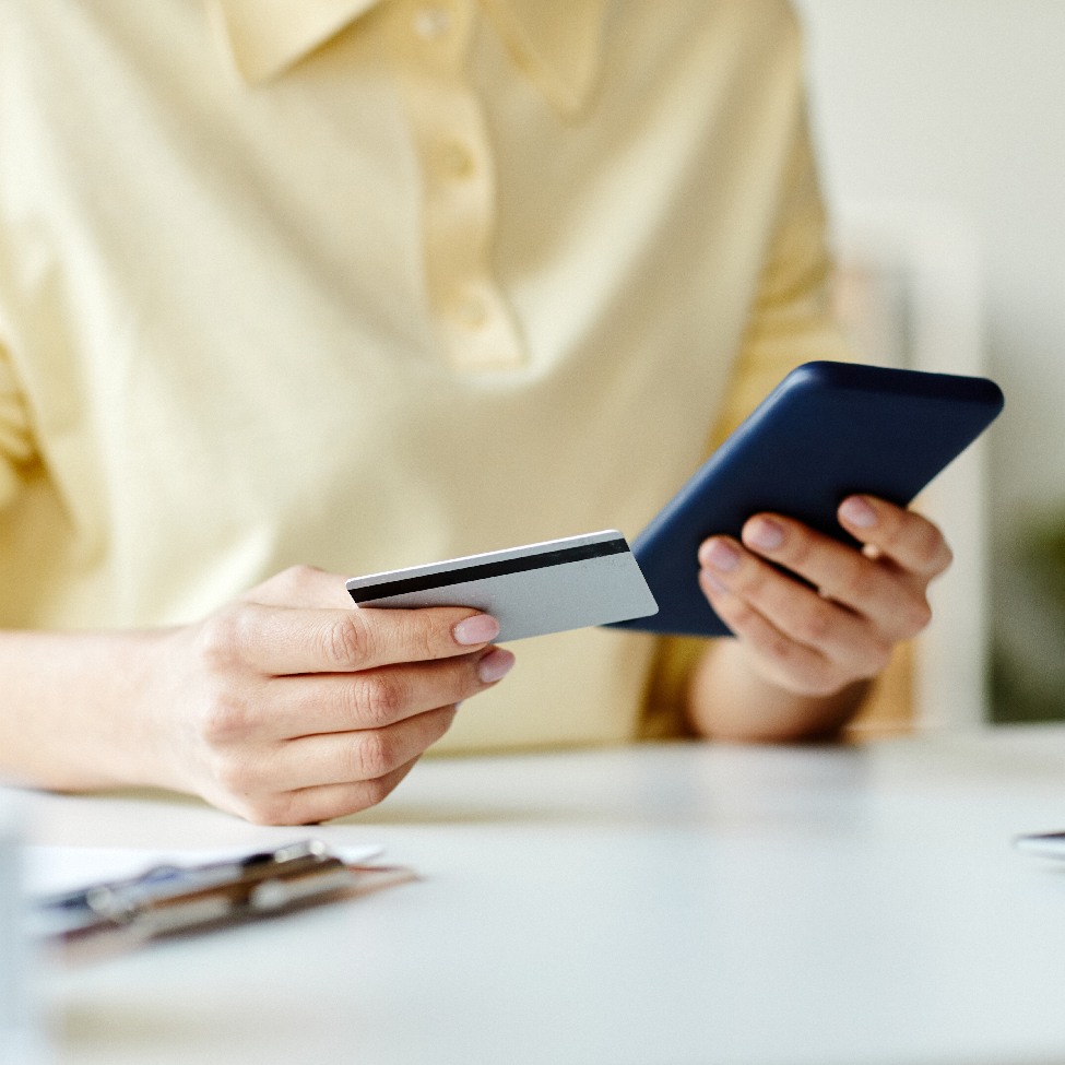 Close up of human hands holding a mobile phone and a debit card