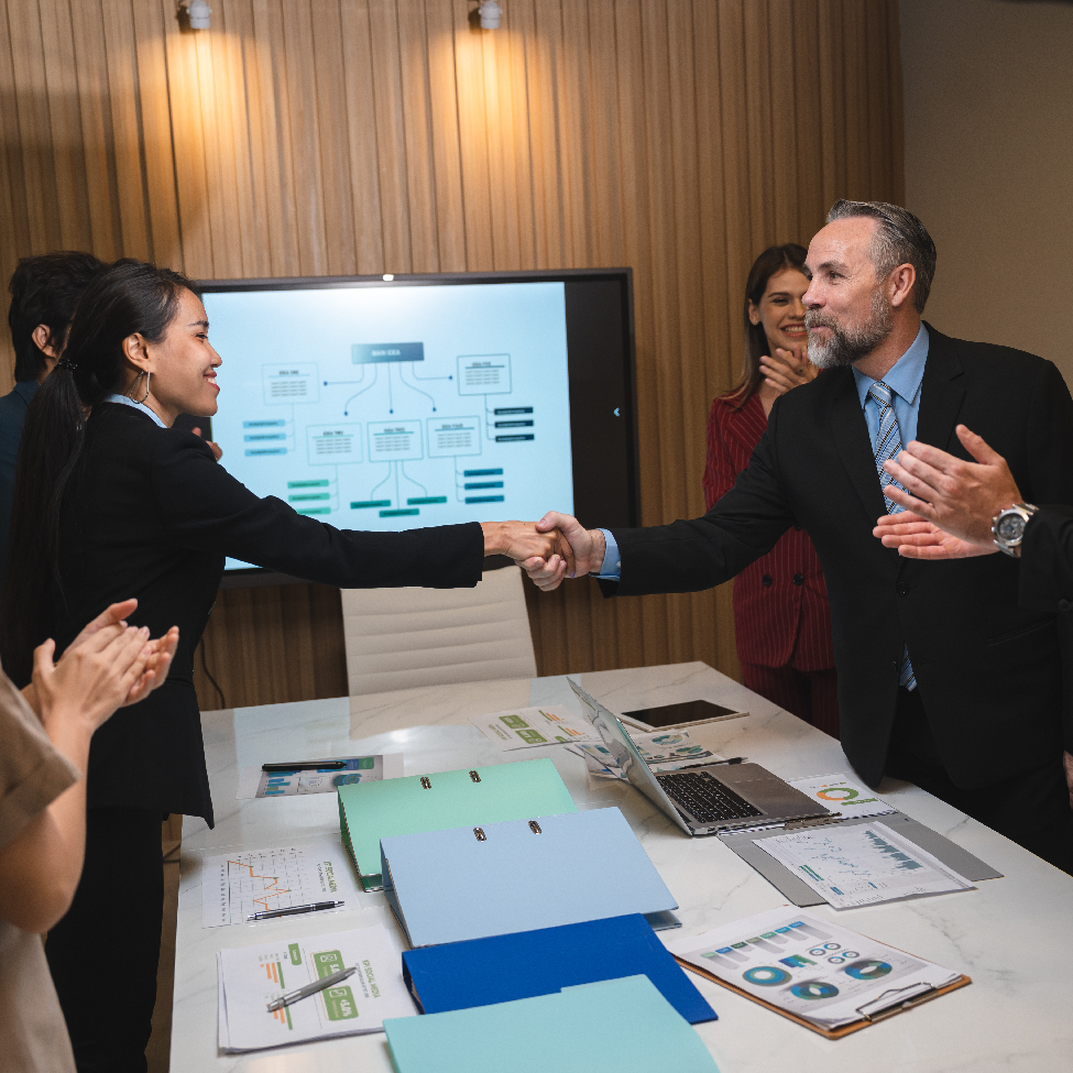 Two insurance IT leaders are shaking hands in a conference room