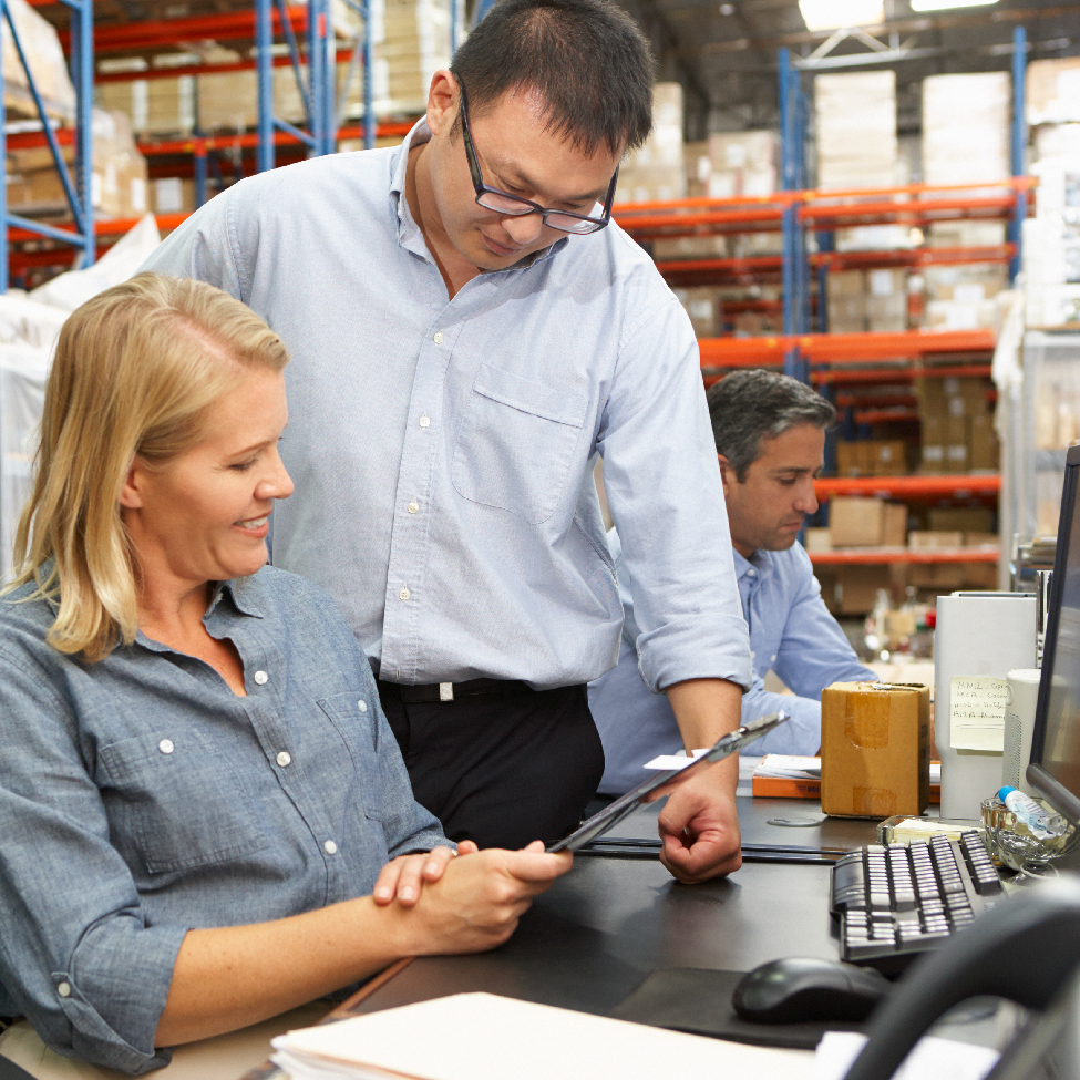 A male and a female engineer discussing report on a tablet in an inventory setting