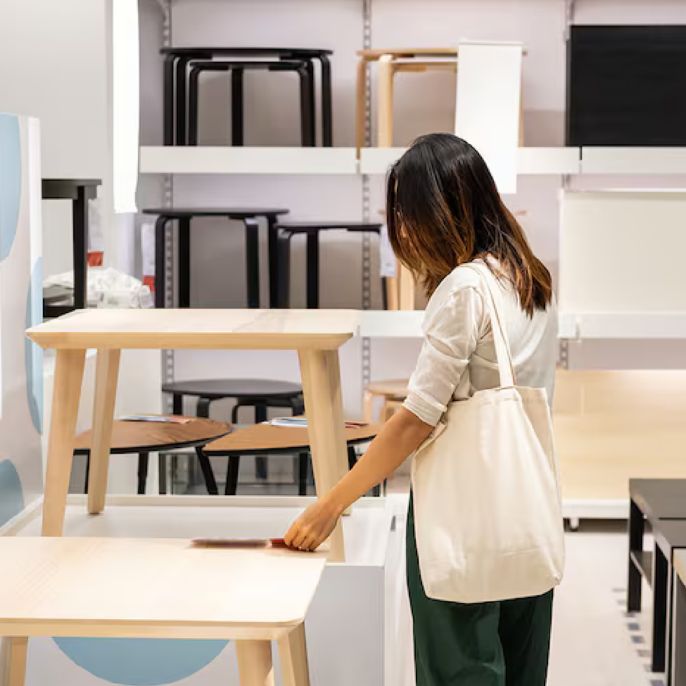 A woman is checking the quality of the wooden tables in furniture retail store