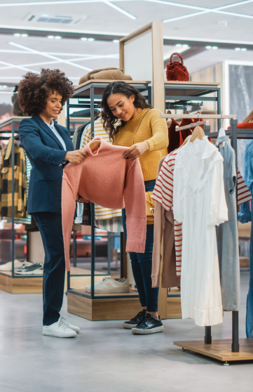 Two women checking out a pink sweater in a retail store