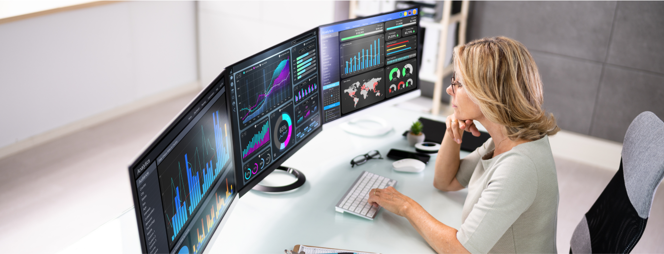 A female IT professional analyzing the data and analytics displayed on her computer screens