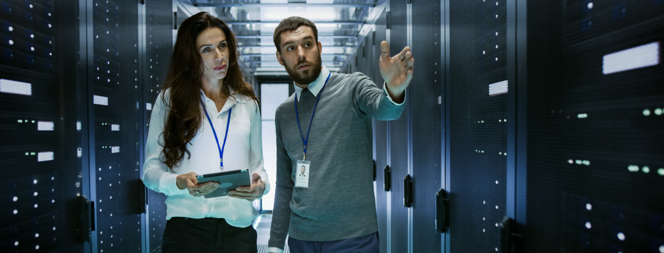 A male and a female IT professional are having a discussion in a server room