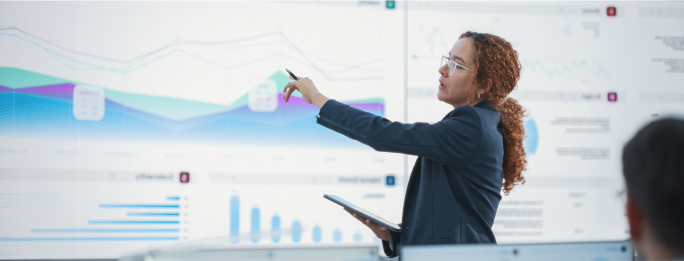 A female IT professional is analyzing data on a large screen in a conference room