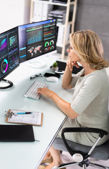 A female IT professional analyzing the data and analytics displayed on her computer screens