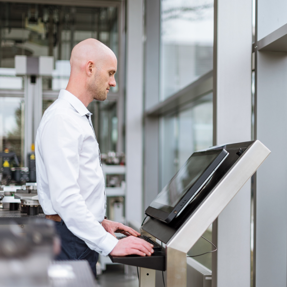 A male IT professional is working on a computer screen