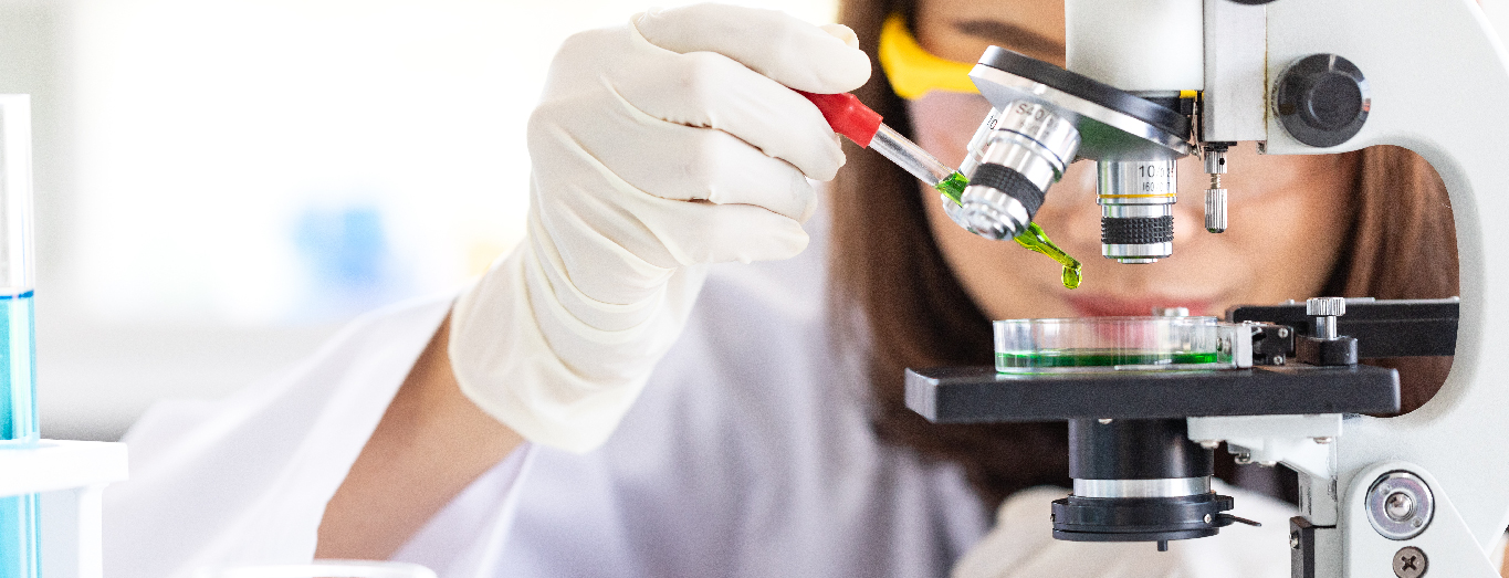 A life science professional examining a liquid solution under a microscope in a life sciences laboratory