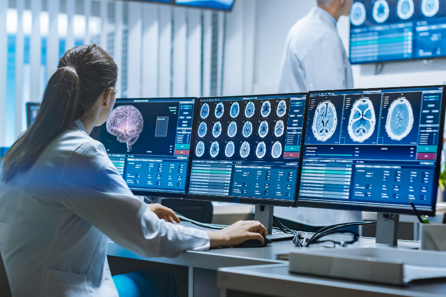 A life science professional working on multiple monitors to analyze medical reports of patient