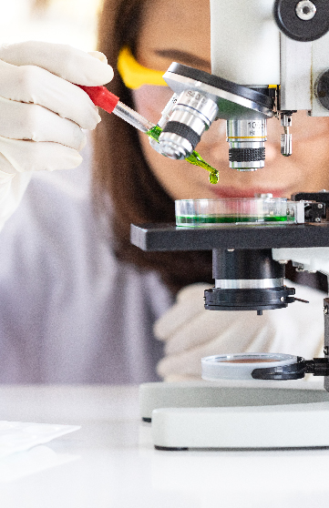 A life science professional examining a liquid solution under a microscope in a life sciences laboratory