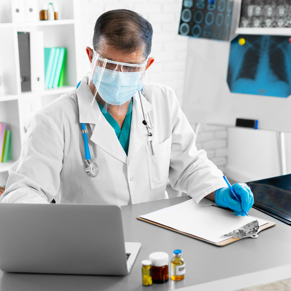 A healthcare professional is analyzing patient data on a computer screen while writing a prescription