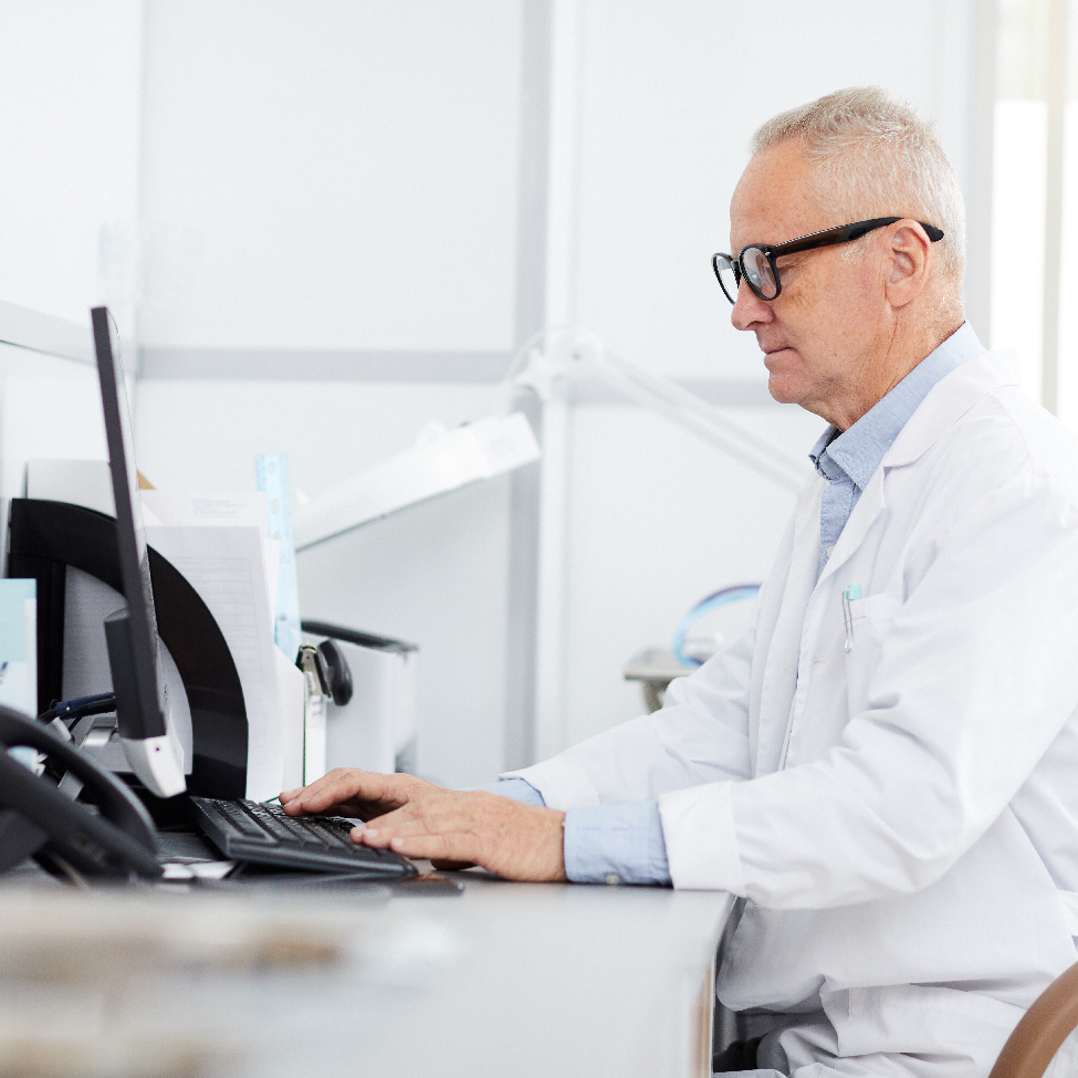 A male healthcare professional is typing on a keyboard in a hospital setting